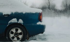 a blue car covered in snow on a snowy day