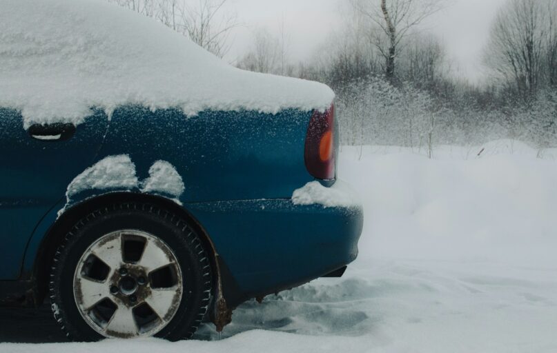 a blue car covered in snow on a snowy day