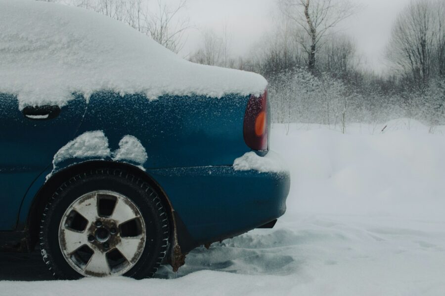a blue car covered in snow on a snowy day