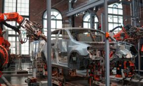 gray vehicle being fixed inside factory using robot machines