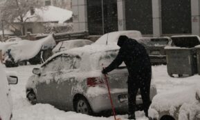 a person shoveling snow off a car
