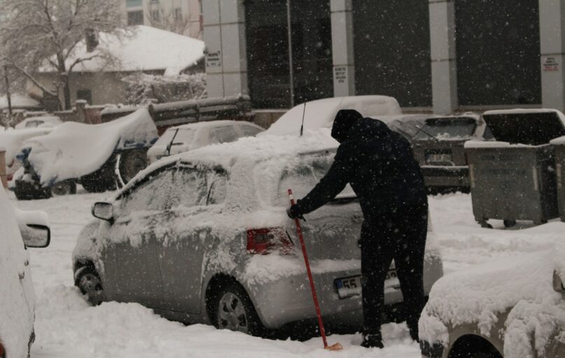 a person shoveling snow off a car