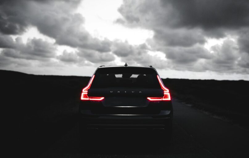 red car on black asphalt road under gray cloudy sky