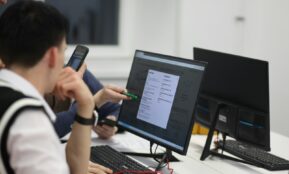 A group of people sitting at a table with computers