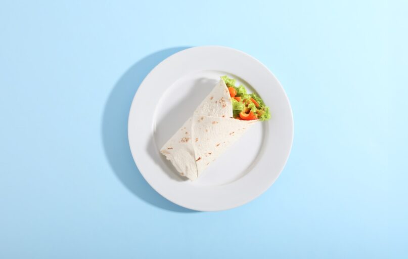 A wrap and salad on a white plate.