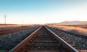 brown train rail under blue sky during daytime