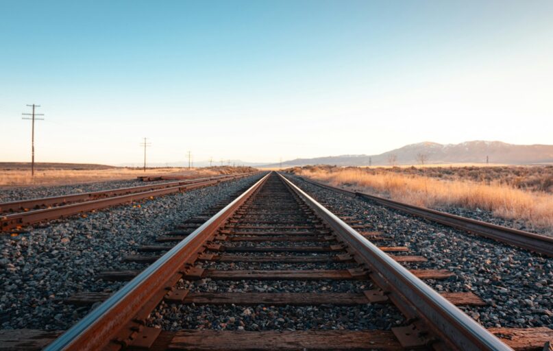 brown train rail under blue sky during daytime