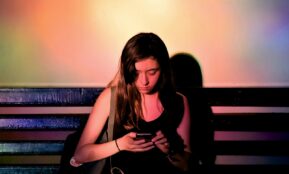 woman wearing black tank dress using smartphone