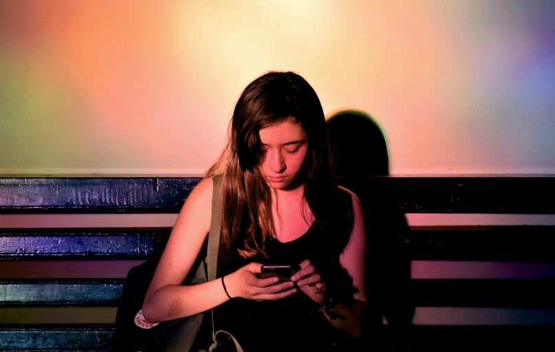 woman wearing black tank dress using smartphone