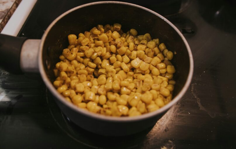 a pot filled with corn sitting on top of a stove
