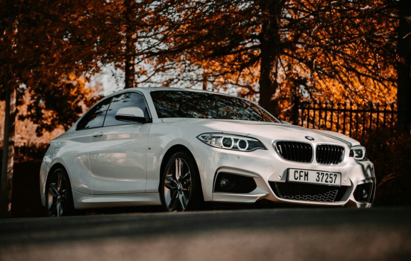 white bmw m 3 coupe parked near brown trees during daytime