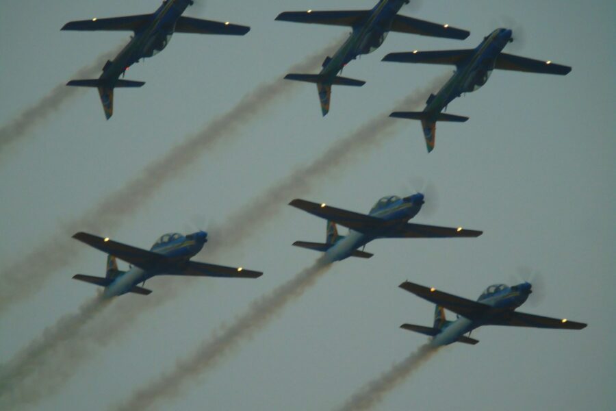 Six airplanes fly in formation, leaving smoke trails.