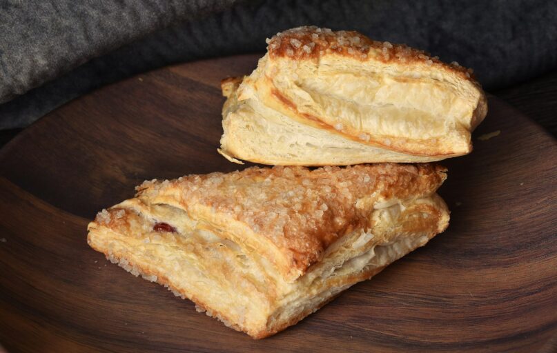 Two pieces of bread sitting on top of a wooden plate