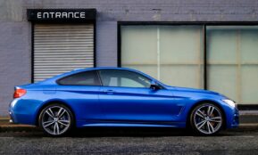 blue coupe beside gray house