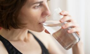 woman in black tank top drinking water