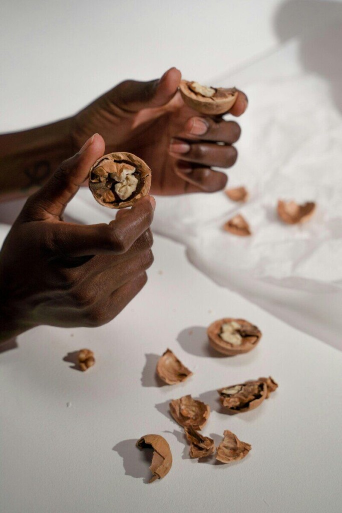 Close-up of hands breaking open walnuts, showcasing natural textures and simple composition.