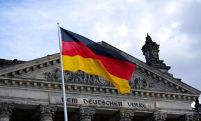 German national flag waving in front of the Reichstag building in Berlin, a symbol of democracy.