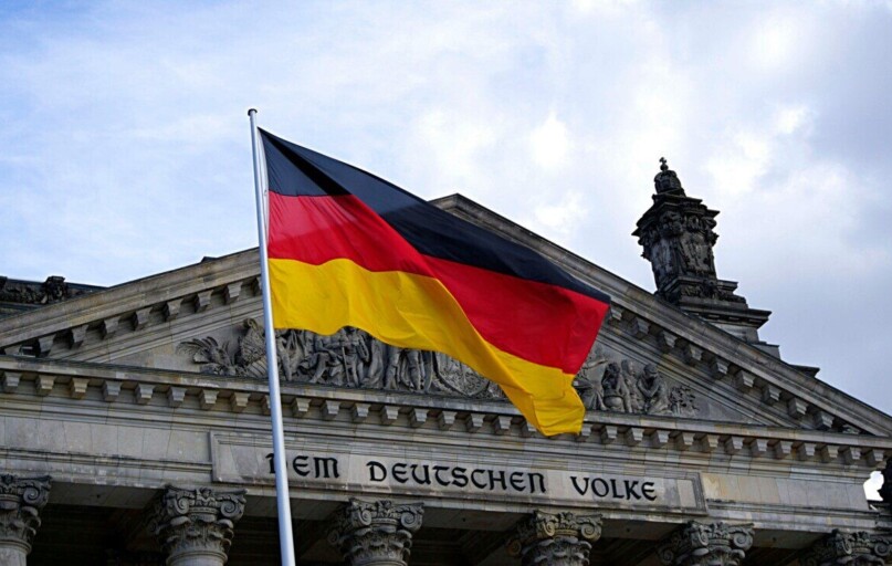 German national flag waving in front of the Reichstag building in Berlin, a symbol of democracy.
