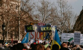 A large crowd holding signs advocating for Ukraine during a daytime protest.