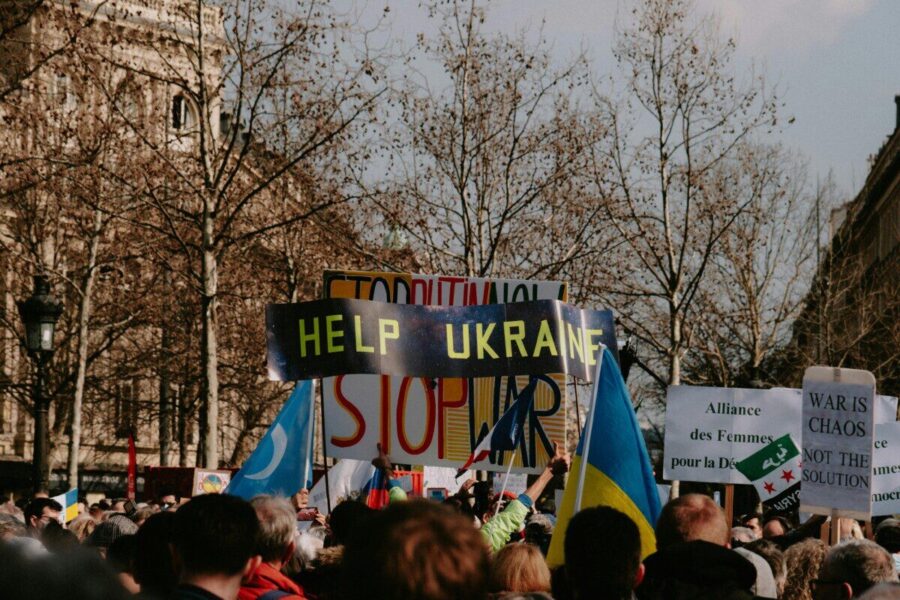A large crowd holding signs advocating for Ukraine during a daytime protest.