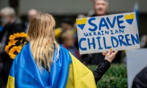 A peaceful protestor holds a 'Save Ukrainian Children' sign in New York City.