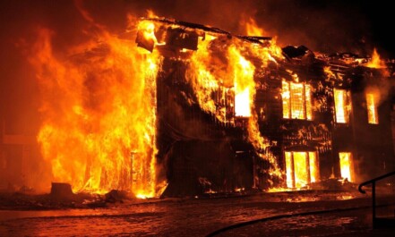 A dramatic nighttime scene of a house engulfed in flames in Tulan, Russia.