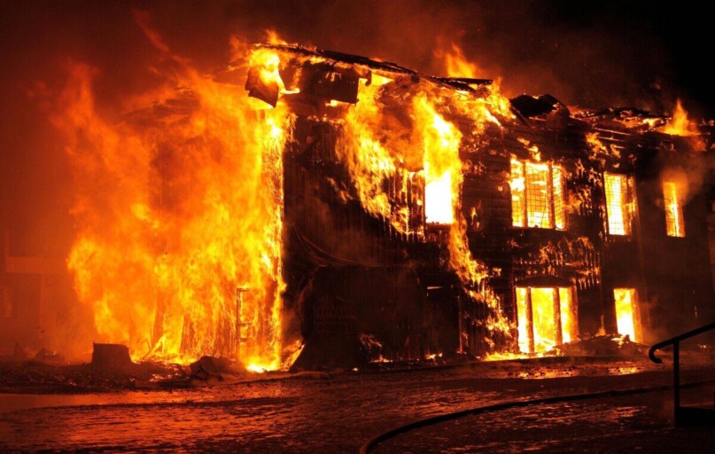 A dramatic nighttime scene of a house engulfed in flames in Tulan, Russia.