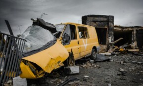 A destroyed yellow van amidst war-torn debris in Borodyanka, Ukraine, illustrating urban devastation.