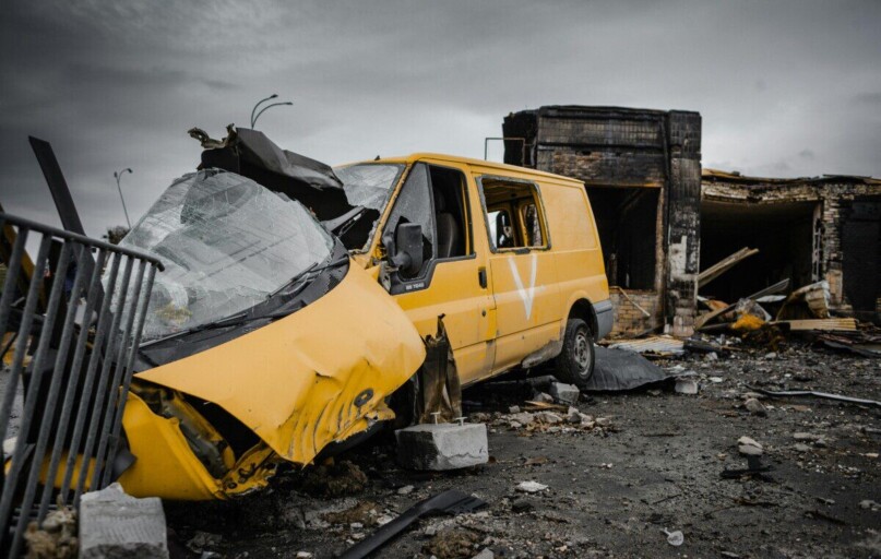 A destroyed yellow van amidst war-torn debris in Borodyanka, Ukraine, illustrating urban devastation.