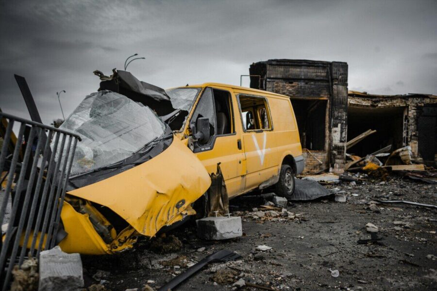 A destroyed yellow van amidst war-torn debris in Borodyanka, Ukraine, illustrating urban devastation.