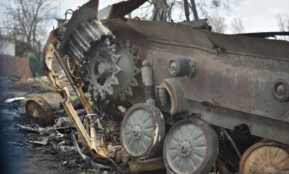 Close-up of a damaged military tank wreckage in an outdoor setting.