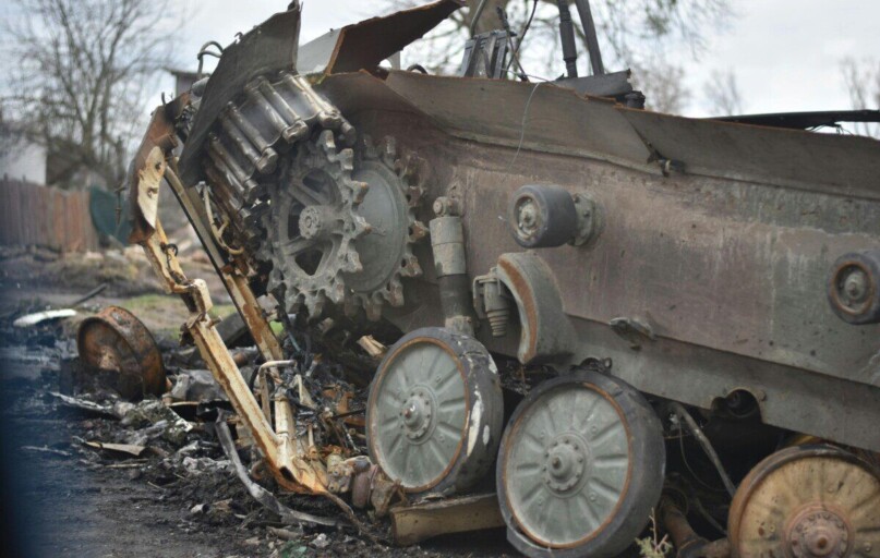 Close-up of a damaged military tank wreckage in an outdoor setting.