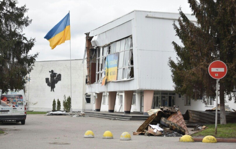 A damaged building with a Ukraine flag depicts the impact of war in an urban area.