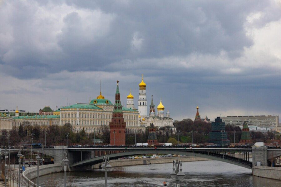 Dramatic view of the Kremlin and Moscow River bridge under cloudy skies, showcasing iconic architecture.