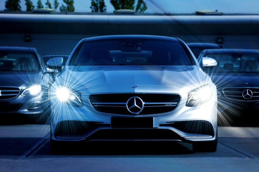 Front view of a lineup of Mercedes-Benz cars with bright headlights, showcasing luxury and elegance.