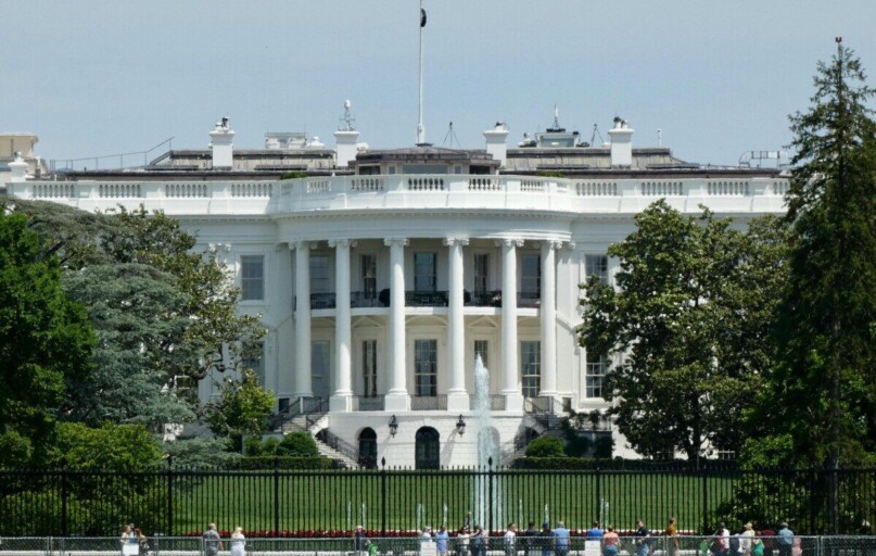 The White House in Washington DC, with tourists viewing from the lawn.