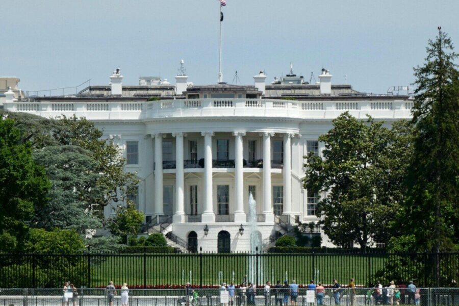 The White House in Washington DC, with tourists viewing from the lawn.