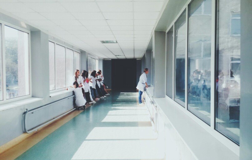 A brightly lit hospital hallway with medical staff in white coats, conveying a professional healthcare environment.
