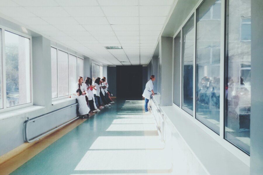 A brightly lit hospital hallway with medical staff in white coats, conveying a professional healthcare environment.