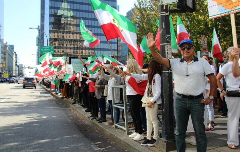 Protesters holding Iranian flags in a peaceful rally on a Vancouver street.