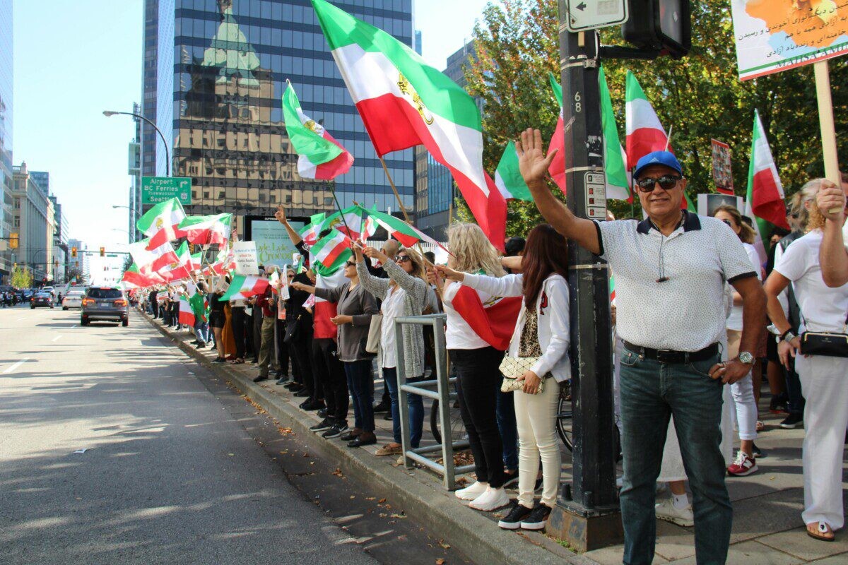 Protesters holding Iranian flags in a peaceful rally on a Vancouver street.