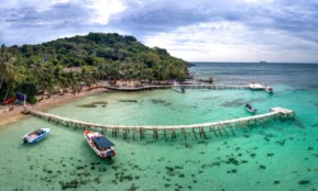 A breathtaking view of a tropical beach with a wooden dock and clear turquoise water.
