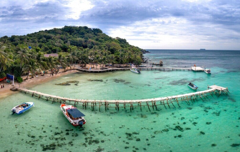 A breathtaking view of a tropical beach with a wooden dock and clear turquoise water.