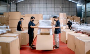Men in a warehouse wearing masks, assembling and packing furniture into boxes with efficiency.