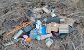 Aerial view of mixed trash and debris scattered in a dry, natural environment.