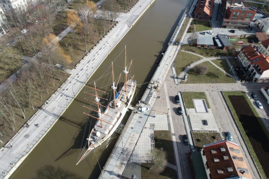 A stunning aerial view of the sailboat Meridian docked in Klaipėda, Lithuania's port.