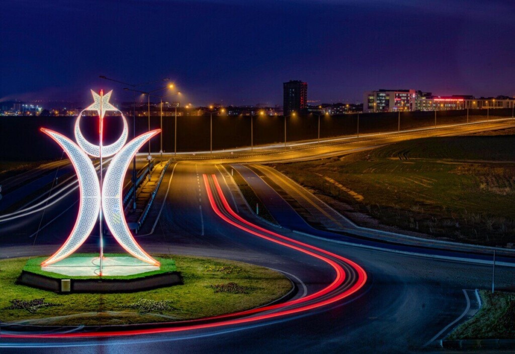 Vibrant night scene of illuminated roundabout and neon sculpture in Edirne, Türkiye.