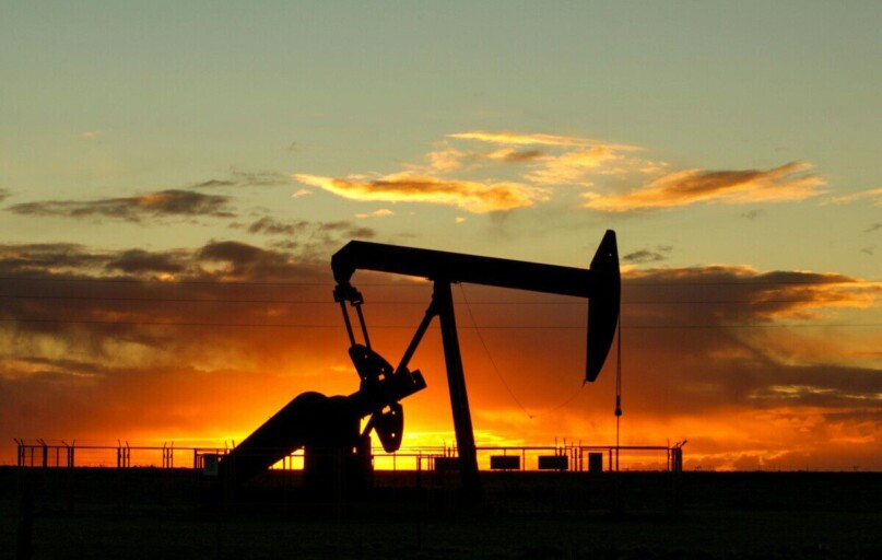 Dramatic silhouette of an oil pump jack against a vibrant sunset sky, emphasizing energy extraction.