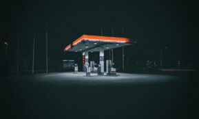 An isolated and illuminated gas station at night, highlighting urban solitude under a dark sky.