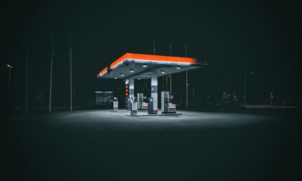 An isolated and illuminated gas station at night, highlighting urban solitude under a dark sky.